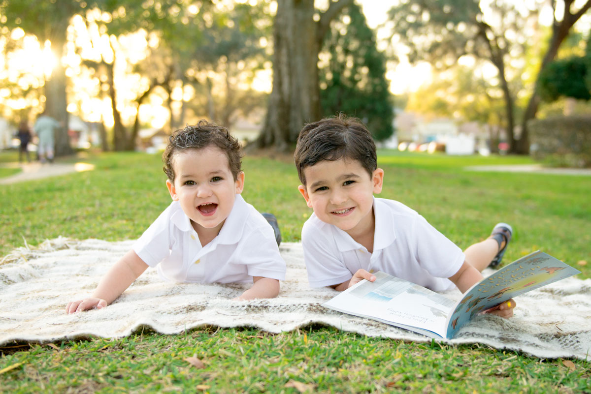 Brothers reading on blanket in park