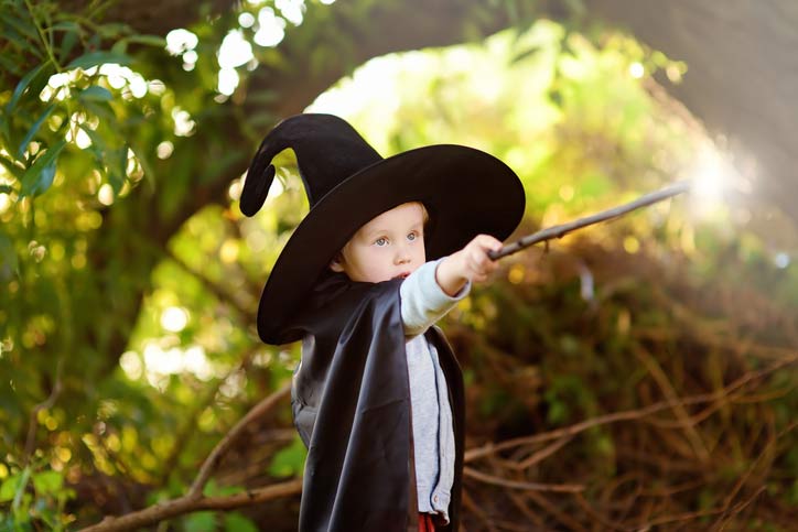 A kid dressed like a wizard holding a wand
