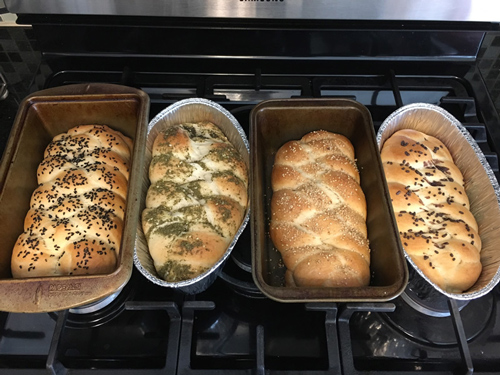 four loaves of challah in bread pans