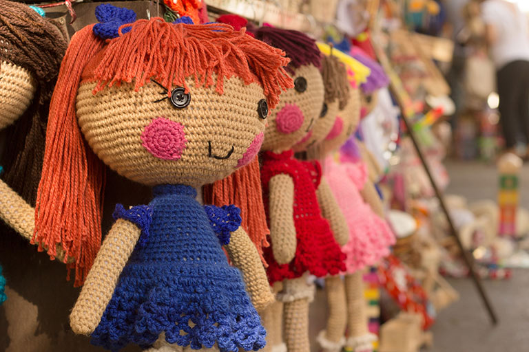 Hand knitted dolls on a sales display.