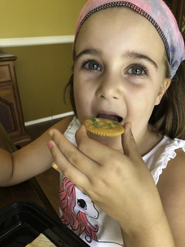 a little girl enjoys a snack of microgreens on crackers