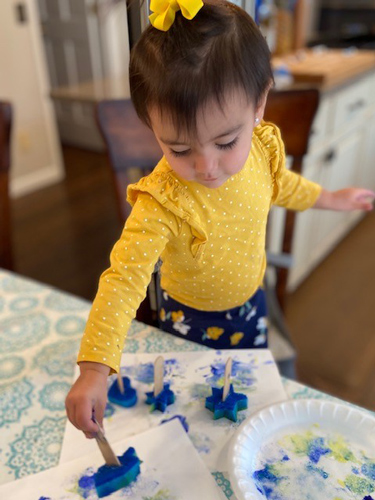 A little girl makes Hanukkah art wiht a homemade stamp