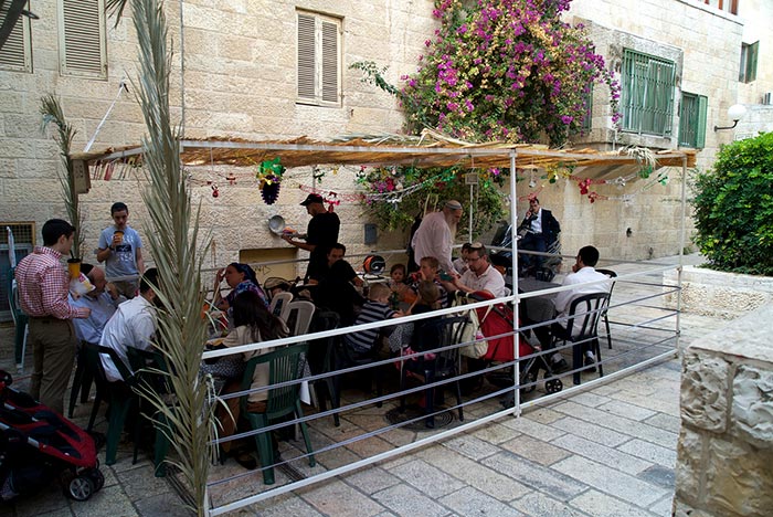 Families dining outdoors in a Sukkah.