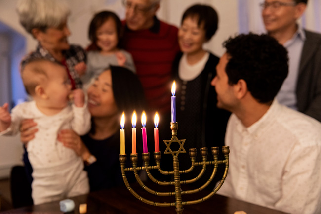 A menorah with five lit candle and a happy family in the background