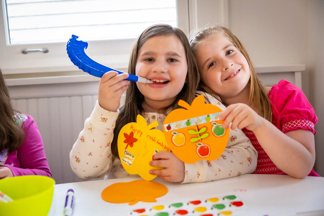 Two kids at a table making Rosh Hashanah crafts