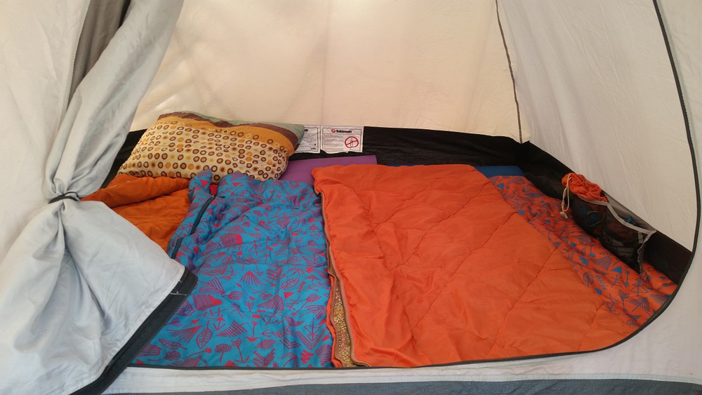Image of the inside of a tent with pillows and blankets