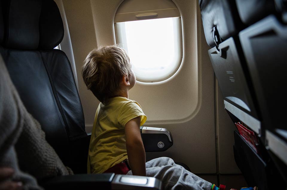 A child looks out the window of a passenger jet.