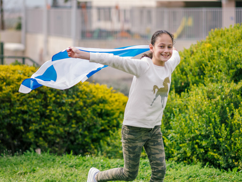 A child running with a flag of Israel streaming behind them