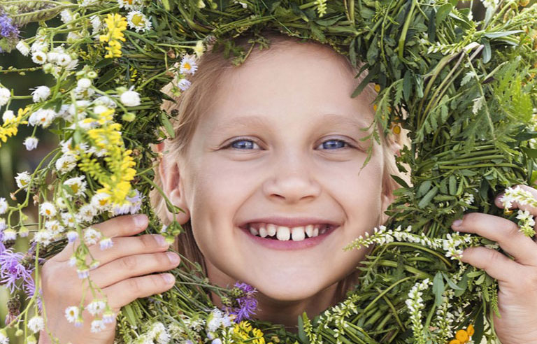 A child looking through a flowery wreath they made.