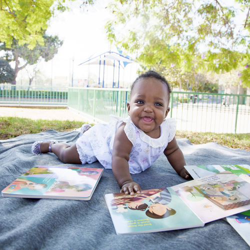 Baby with a picture book outside on a blanket