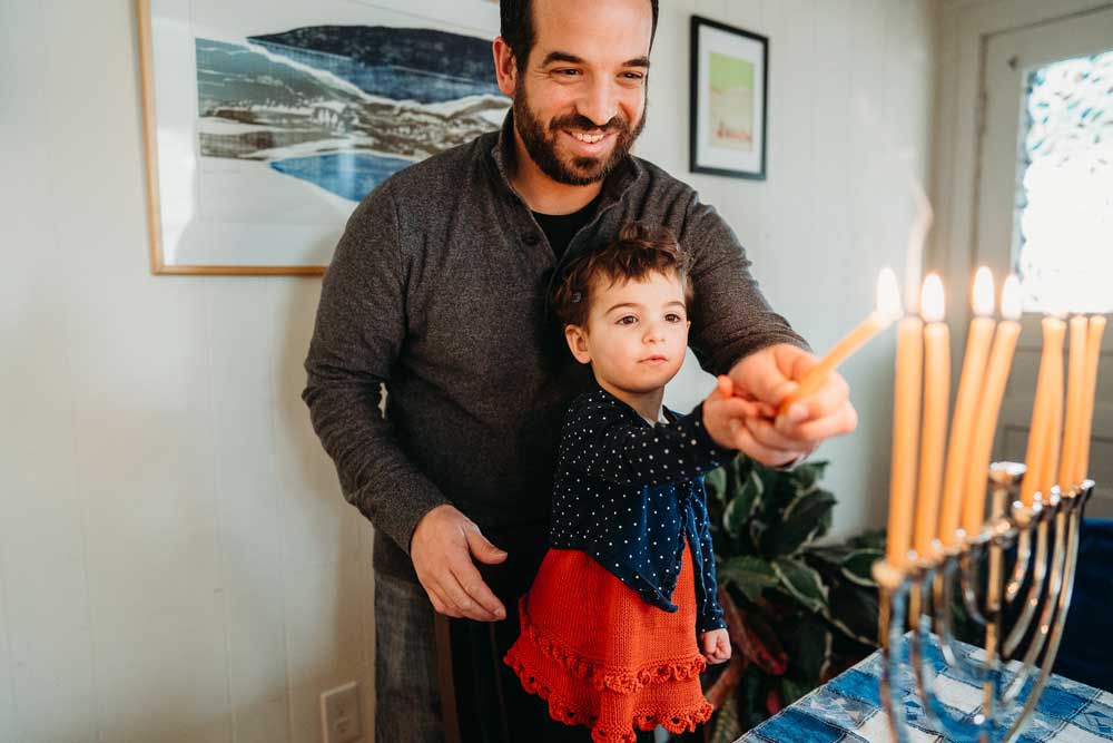 Father and daughter lighting menorah together