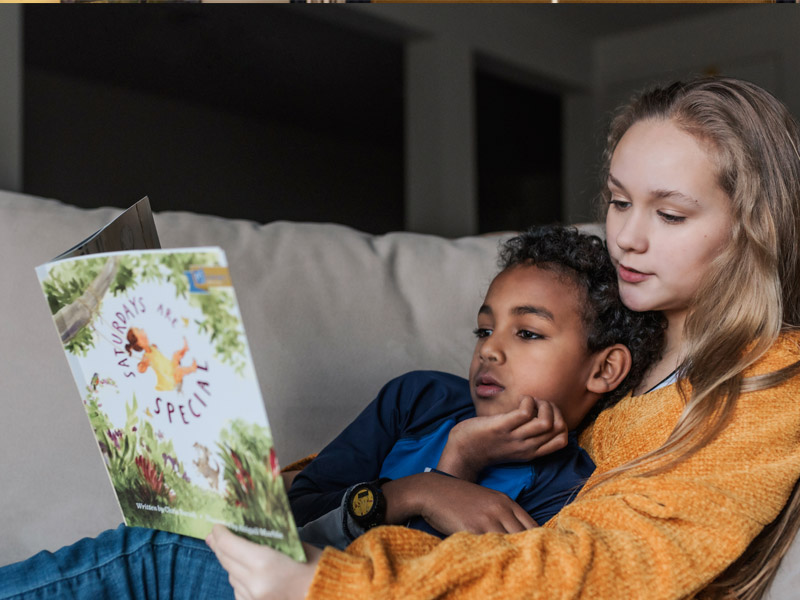 Two children standing at a table dressed for Shabbat