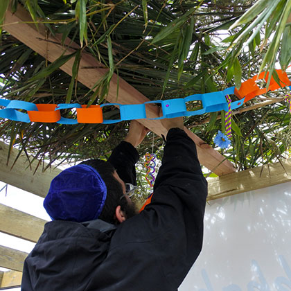 A person building and decorating a sukkah