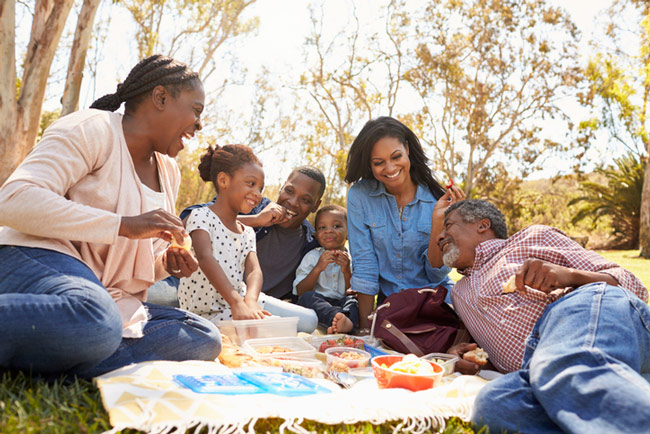 A family laughs together while enjoying a picnic