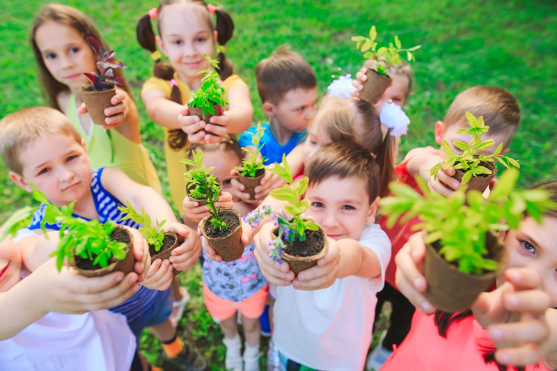 Kids holding newly potted plants