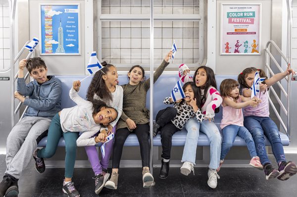 A group of children rides the subway waving Israeli flags