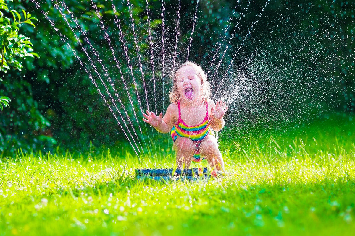 Young Girl Playing in Sprinkler