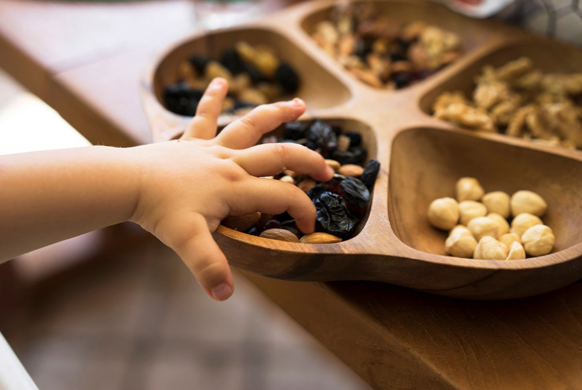 Child's hand grabbing raisins and nuts