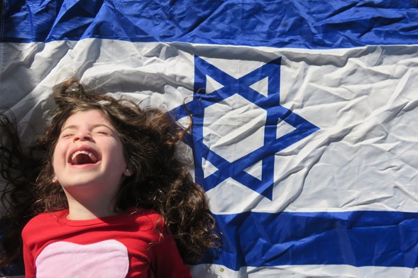 laughing child against backdrop of Israeli flag