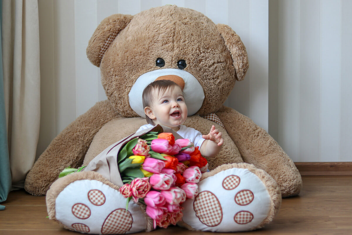 Baby sitting with a giant teddy bear