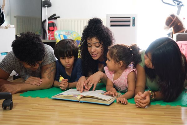 Family looking at books together on the living room floor