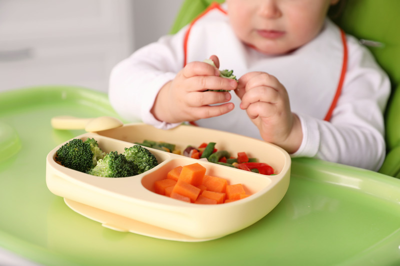 A baby eating a veggie plate