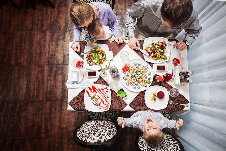 Bird's eye view of a family eating a colorful meal at a table.