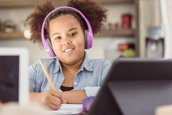 Little girl wearing headphones and filling out an activity sheet
