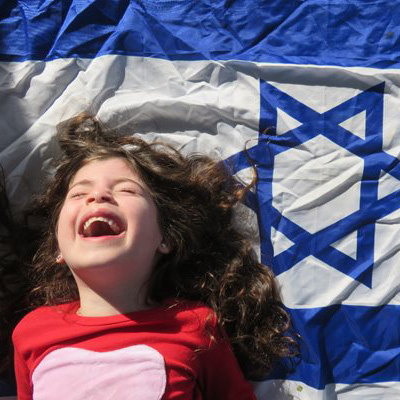 A girl smiling in front of an Israeli flag
