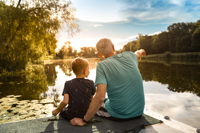 Young boy and his grandfather spending time at the lake
