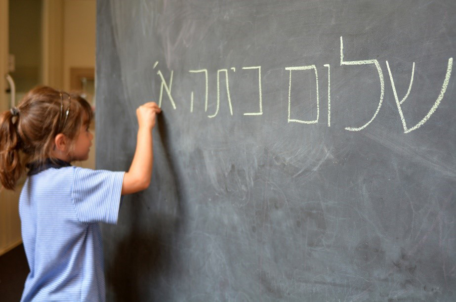 Girl writing hebrew on a chalkboard