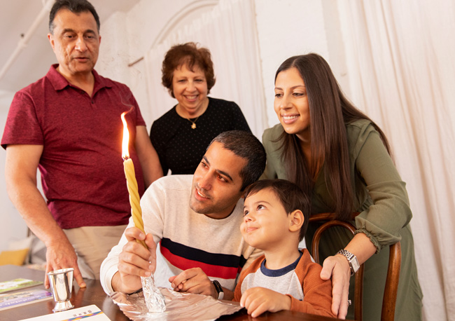 A family gathered at a table with a lit Havdalah candle