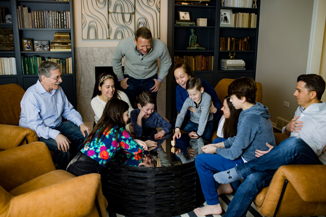 A family gathered around a table playing with a dreidel