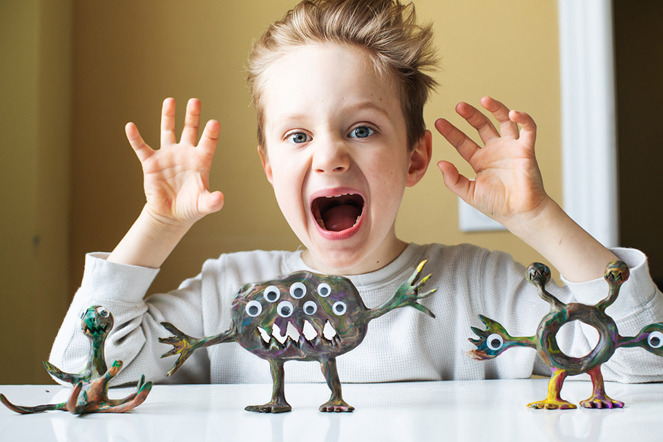 Child Playing with Monster Sculptures