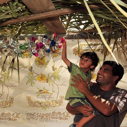 A father and his child decorating their sukkah