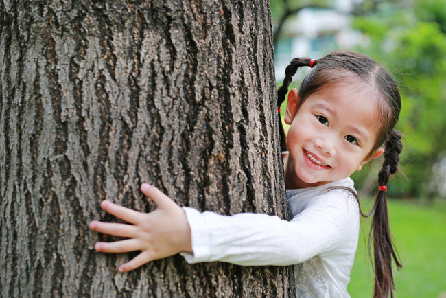 A happy asian girl hugging a tree