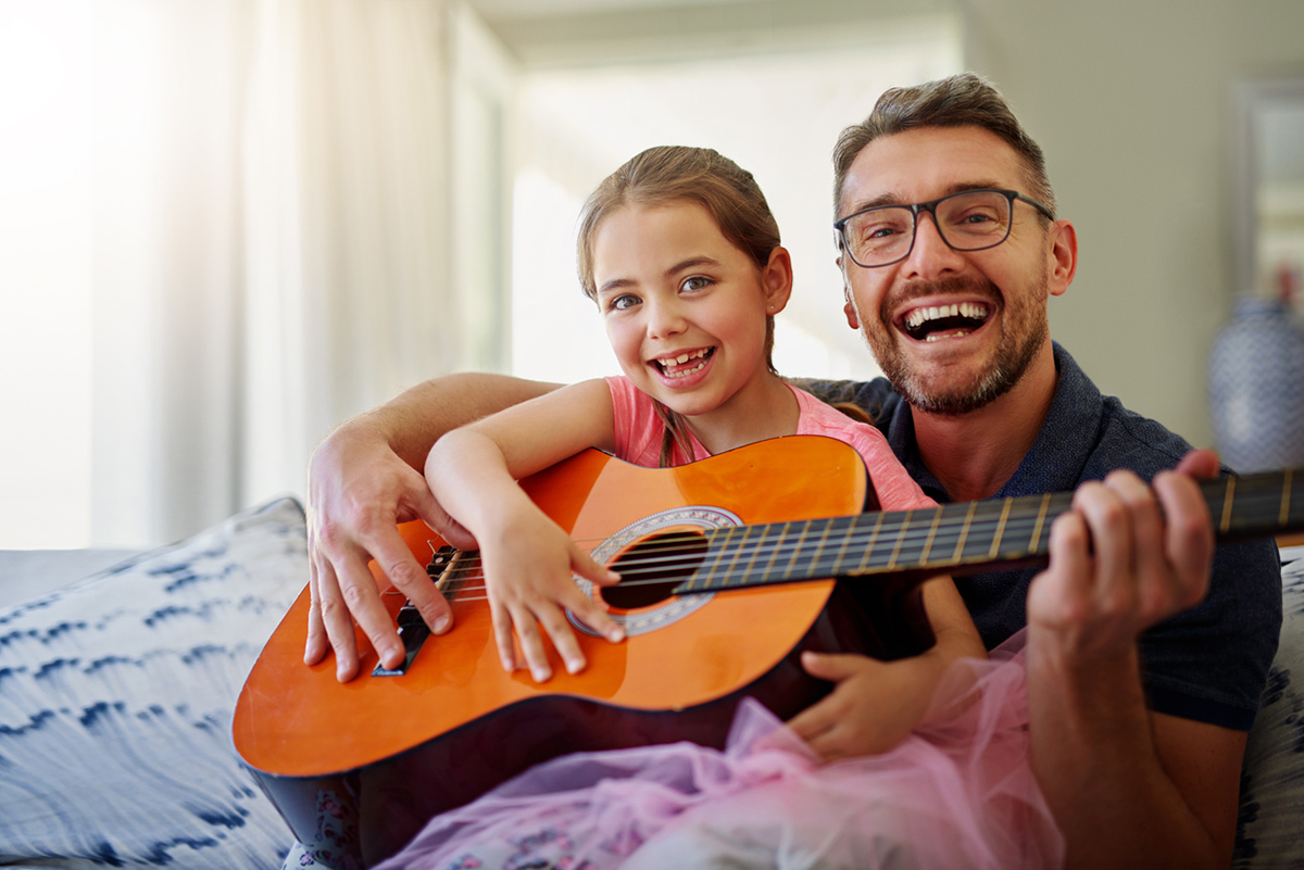 Dad playing guitar with daughter