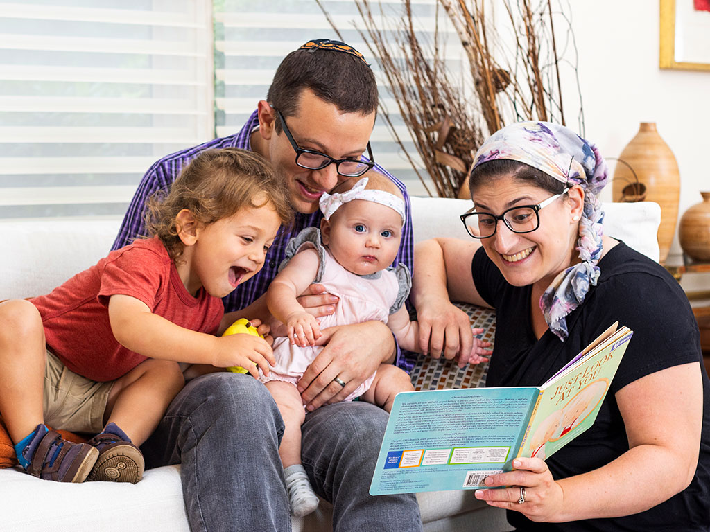 A happy family sits together reading a book
