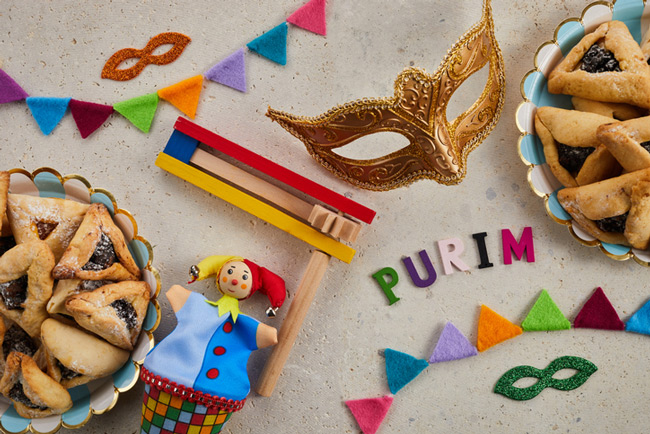 A mask, some rugelach, and other purimspeil items on a table.