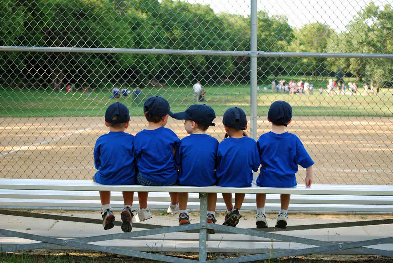 kids sitting on baseball bench
